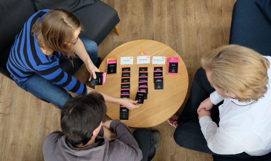 Mission Cards im Einsatz. Ein Team beantwortet die Fragen der Karten, legt an, verschiebt und sortiert aus, bis der Plan für den Onlineshop steht.