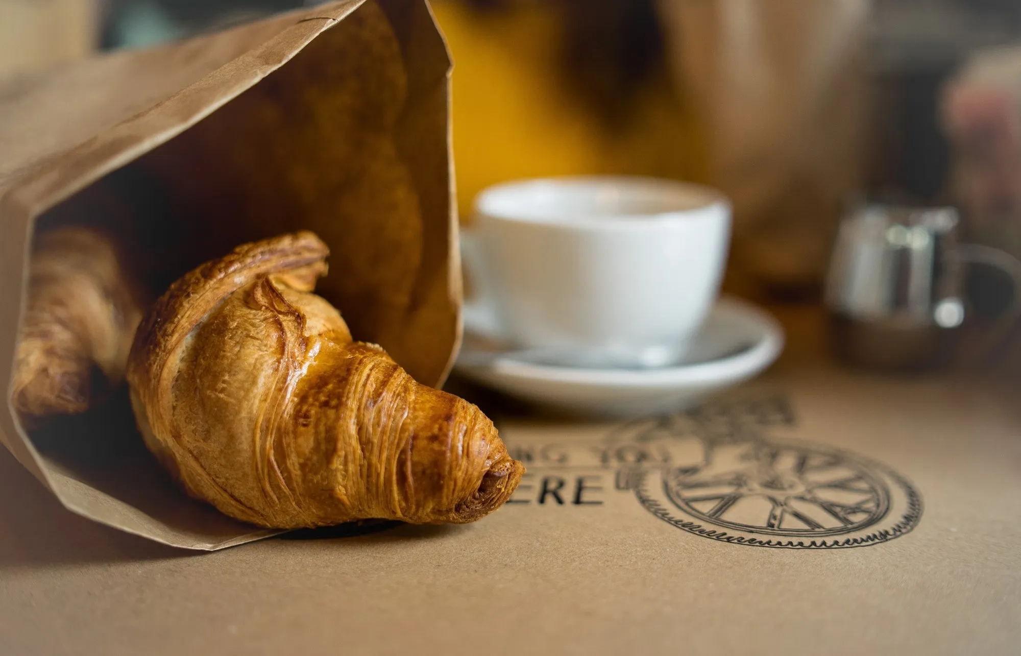 Brownbag mit Croissants und Kaffee auf einem Tisch
