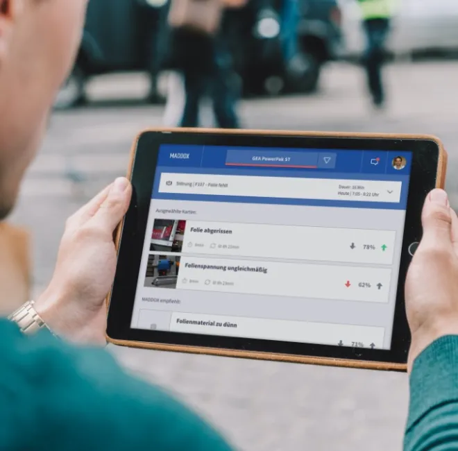 Jemand hält ein Tablet, auf dem Maddox gestartet wurde. Maddox lernt durch eine KI vom Anwender und unterstützt anschließend bei Fehlermeldungen.