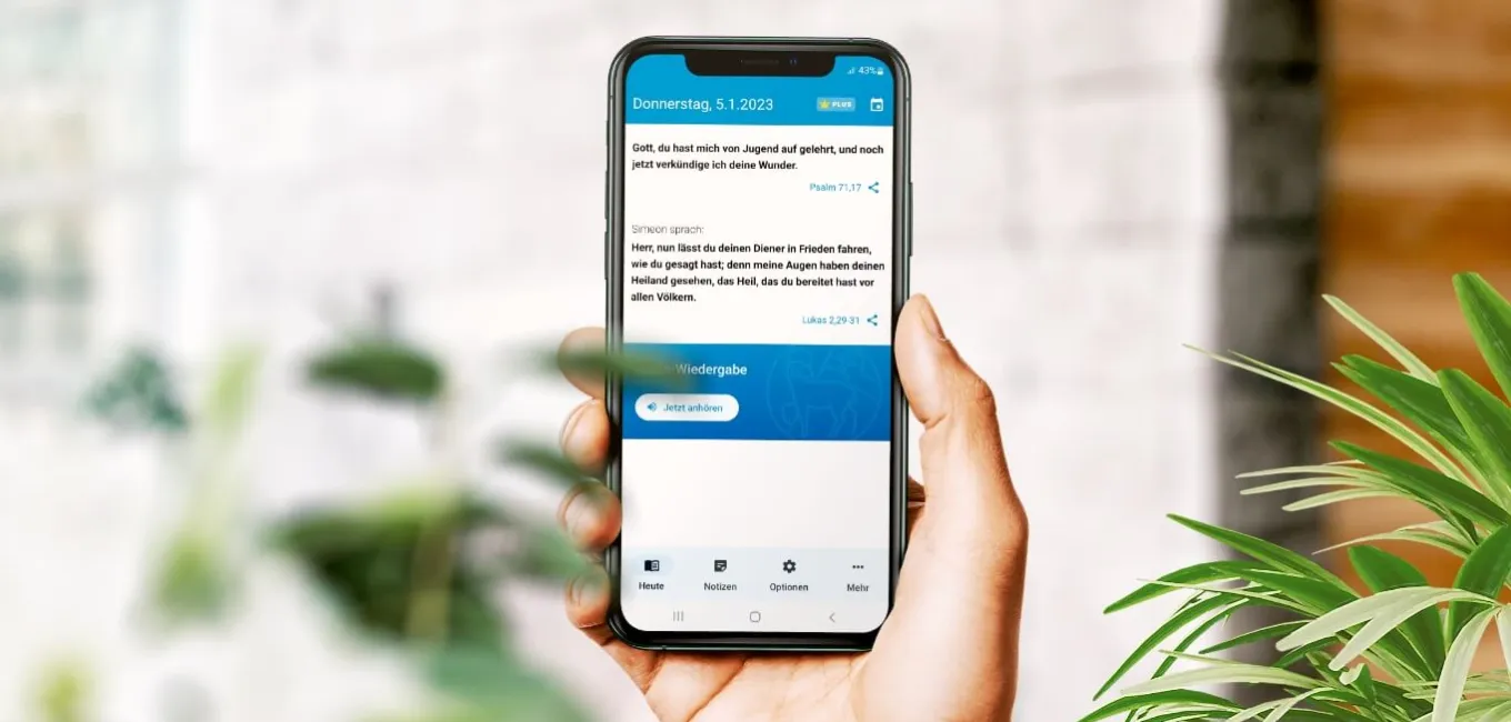 Hand hält ein Smartphone mit geöffneter Losungen App. Der Startbildschirm mit Gottes Wort für jeden Tag ist zu lesen. 